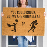 a woman holding a door mat that says you could knock but we are probably at
